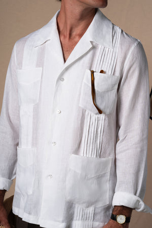 Nuestra guayabera blanca claro reinterpreta una de las camisas más emblemáticas del verano con una estética cuidada y contemporánea. Confeccionada en 100% lino, lo que le aporta ser un producto fresco, ligero y con una caída impecable, perfecta para acompañarte con estilo en los días más cálidos.

Su estructura incorpora ocho alforzas tanto en la parte frontal como trasera. Dispone de cuatro bolsillos funcionales (dos en pecho, dos en cintura), detalles tradicionales de la guayabera original, que refuerzan 